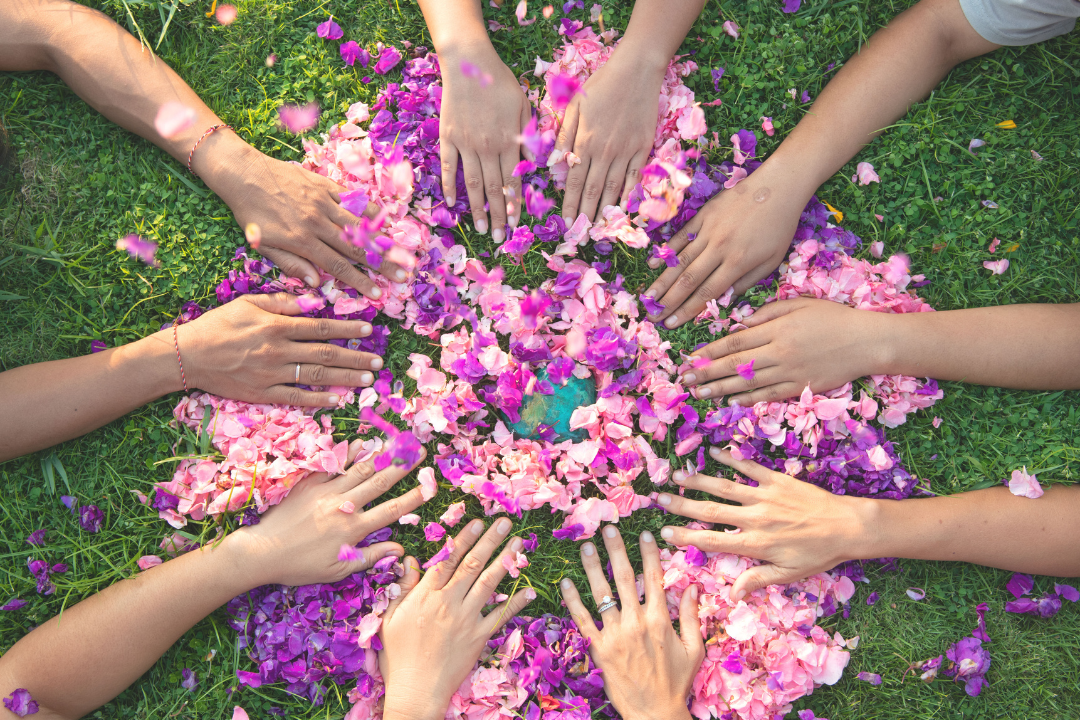 hands in a circle with flowers